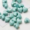 Macro view of heart-shaped ceramic beads with marble texture and polished green finish - Lake Green