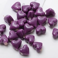 Macro shot of glossy purple heart-shaped ceramic beads for DIY jewelry making - Purple