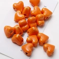 Close-up of bright orange heart-shaped ceramic beads for DIY jewelry making - Orange