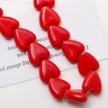 Gros plan de perles en céramique rouges brillantes en forme de cœur pour bijoux DIY - Rouge