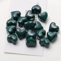 Close-up of glossy dark green heart-shaped ceramic beads with side holes for DIY jewelry - Dark Green