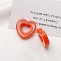 Detail showing orange layered heart resin charms on a white ceramic plate for DIY jewelry - Orange Heart