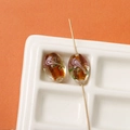 Detailed view of handmade oval glass beads with floral gold foil inlay for DIY jewelry - 1 Piece (17x12mm) / Brown