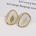 Close-up of handmade oval resin earrings with green dried leaves and pearls - Pearl White With Green Leaf