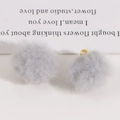 Close-up of soft grey plush pom-pom charms with gold metal rings for DIY jewelry - Space Gray