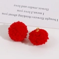 Macro view of fluffy red pom-pom jewelry pendants with a gold metal loop and soft texture - Fluffy Red