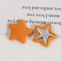 Detailopname van feloranje gebreide stervormige accessoires met zilveren steraccenten - Oranje