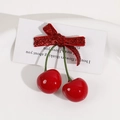 Detail of glossy red cherry hair accessory with a sparkling bow on a white plate - Bright Red Bow Cherry