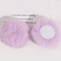 Close-up of two light purple 50mm faux rabbit fur pompoms with white adhesive backing pads - Light Purple