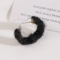 Detail view of C-shaped earrings wrapped in black plush wool with gold metal pins - Black