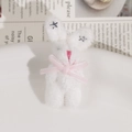 Gros plan d'un pendentif lapin en peluche blanc avec nœud rose et détails étoilés - Blanc