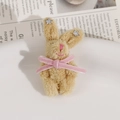 Détail d'un charm lapin en peluche kaki avec nœud rose et étoiles en cristal - Marron