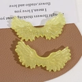 Macro view of glittering yellow angel wing acrylic charms on textured leather background - Yellow