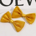 Detalle de pinzas de pelo doradas con purpurina, textura suave y diseño de lazo de doble capa - Amarillo Brillante