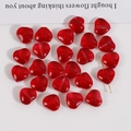 Makroaufnahme von roten herzförmigen Glasperlen mit goldenem T-Stift für DIY Schmuck - Rot