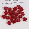 Nahaufnahme einer durchscheinenden roten herzförmigen Glasperle für DIY-Schmuckherstellung - Fuchsie