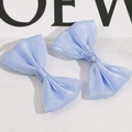 Macro view of two light blue double-layered mesh bow hair accessories on a white base - Blue