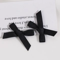 Détail de deux barrettes à nœuds en tissu noir fait main sur une carte décorative blanche - Noir