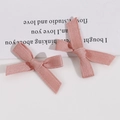 Vue détaillée de deux pinces à cheveux avec nœuds en tissu rose faits à la main sur carte - Rose foncé