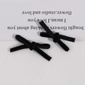 Macro detail of two black velvet handmade bow hair clips on a minimalist beige background - Black
