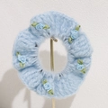 Blue knit hair scrunchie with five handmade ribbon roses on a metal display stand - Blue