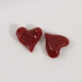Macrodetail van glanzende donkerrode onregelmatige hartbedeltjes van hars voor DIY sieraden - Rood