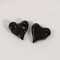Close-up of glossy black heart resin charms with a smooth reflective mirror surface - Black