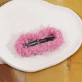 Close-up of pink fuzzy plush BB hair clip on a white ceramic plate for winter hair styling - Pink