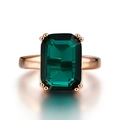 Close-up of a large emerald-cut green gemstone ring with a rose gold plated band and reflection - Number 9 / Rose Gold Green Zirconia