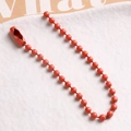 Detail of red coated metal ball chain showing uniform round beads and connector clasp - Orange
