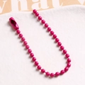 Macro shot of rose pink ball chain necklace with metal connector on white tray - Rose Red