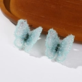 Detailed close-up of blue crystal butterfly earrings with green gem centers on wood - Light Green