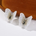 Macro detail of white translucent butterfly earrings with sparkling crystal textures - White