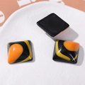 Close-up of square resin DIY accessory with black and tri-color fluid sand textures - Square Black Yellow Orange