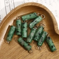 Macro shot of green stone cylinder pendants with metal rings on vintage poem paper - Green Spotted Stone Style (No. 3)