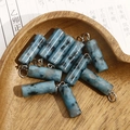 Macro shot of blue spotted natural stone cylinder pendants in a wooden heart-shaped tray - Sky Blue Spotted Stone Style (No. 4)