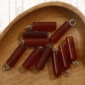 Macro shot of red agate cylinder pendants in a wooden bowl on calligraphy paper - Red Agate Style (No. 5)