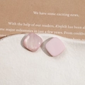 Gros plan de breloques en résine carrées roses avec texture nacrée sur un plateau en céramique - Carré Rose Clair
