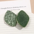 Detail of leaf-shaped resin accessories with hammer texture and green glitter shimmer - Green
