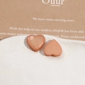 Macro view of peach pearlescent heart resin charms on a white ceramic display tray - Orange Heart