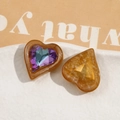 Makro-Detail von bernsteinfarbenen Herzanhängern aus Harz mit Kristallen für DIY-Schmuck - Dunkelorange