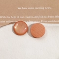 Close-up of coral orange round resin buttons with pearlescent and matte finish on a tray - Orange Round