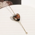 Dettaglio macro di una perla a cuore in vetro bicolore su uno spillo dorato - Stile Cuore Lampwork