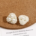 Detailed view of handmade pearl cluster earrings in elegant white on cork background - Triangle Pearl Style