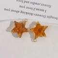 Macro-opname van amberkleurige sterhangers van hars met ruittextuur en gouden ringen - Oranje