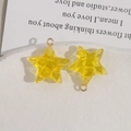 Macro-opname van gele sterhangers met ruittextuur en metalen ringen voor DIY-sieraden - Geel
