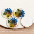 Makroaufnahme transparenter Harzohrringe mit echten blauen und gelben Trockenblumen - Blau