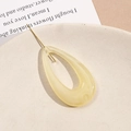 Macro shot of drop-shaped acrylic earring charms with marble texture on a beige plate - Beige