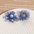 Gros plan de boucles d'oreilles en cristal bleu et perles blanches sur plat céramique - Pince étoile bleue cartoon (Cinnamoroll)