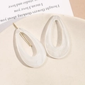 Elegant teardrop acrylic earrings with white marble texture and gold pins on stone tray - White